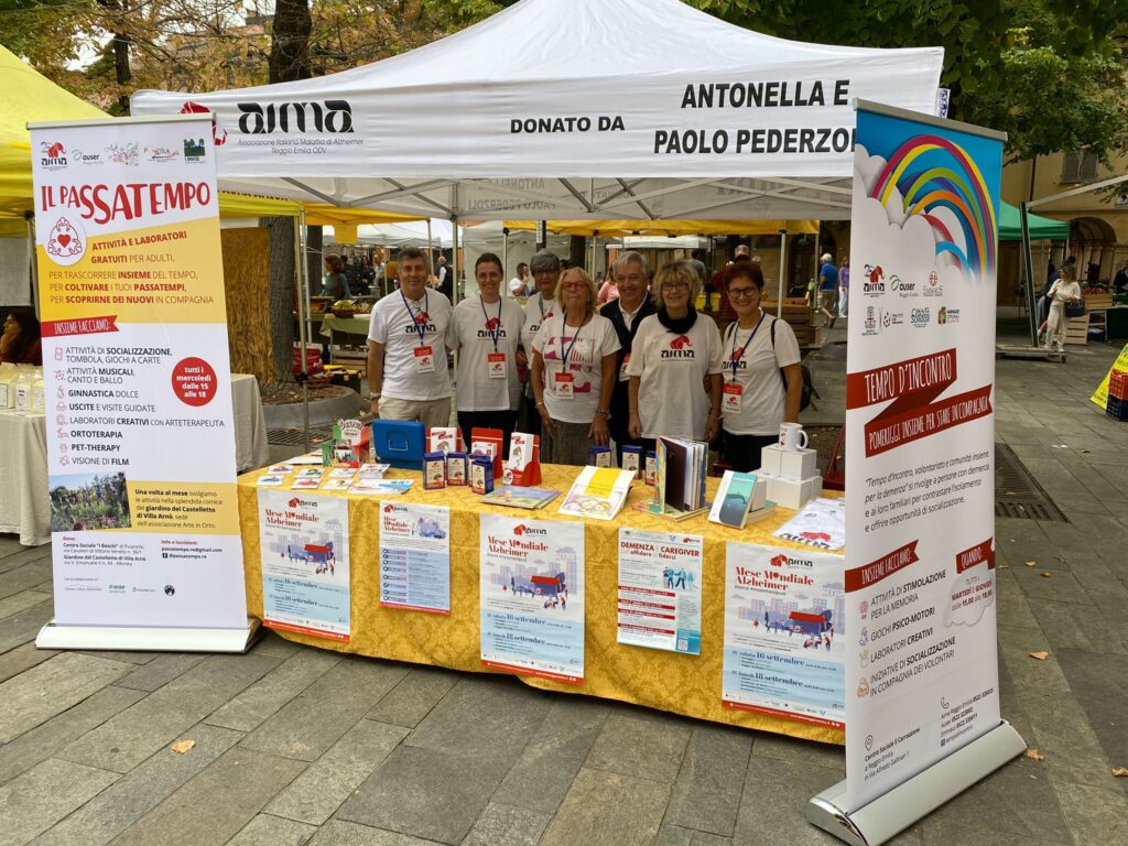 Fotografia dello stand con i volontari di AIMA Reggio Emilia per la campagna #insiemesipuò del Mese Mondiale Alzheimer in piazza Fontanesi a Reggio Emilia