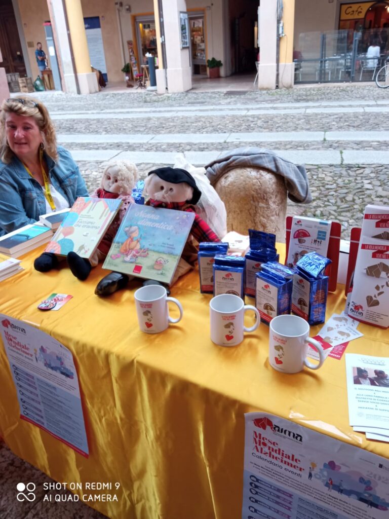 Fotografia dello stand con i volontari di AIMA Reggio Emilia per la campagna #insiemesipuò del Mese Mondiale Alzheimer a Correggio