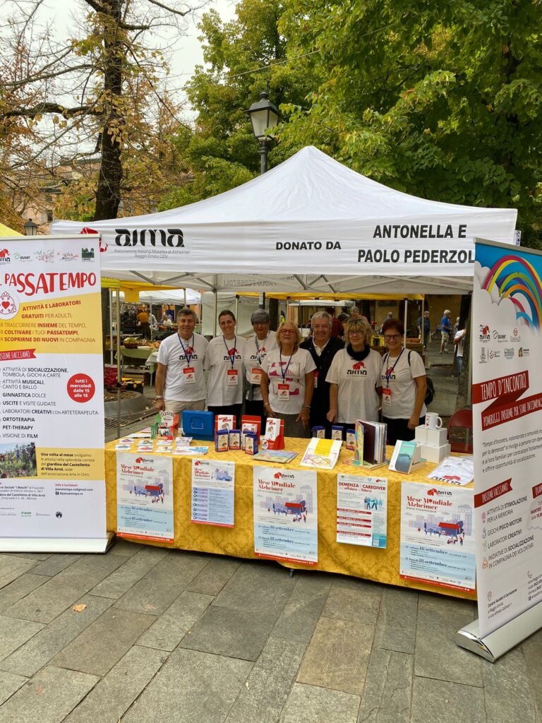Fotografia dello stand con i volontari di AIMA Reggio Emilia per la campagna #insiemesipuò del Mese Mondiale Alzheimer in piazza Fontanesi a Reggio Emilia