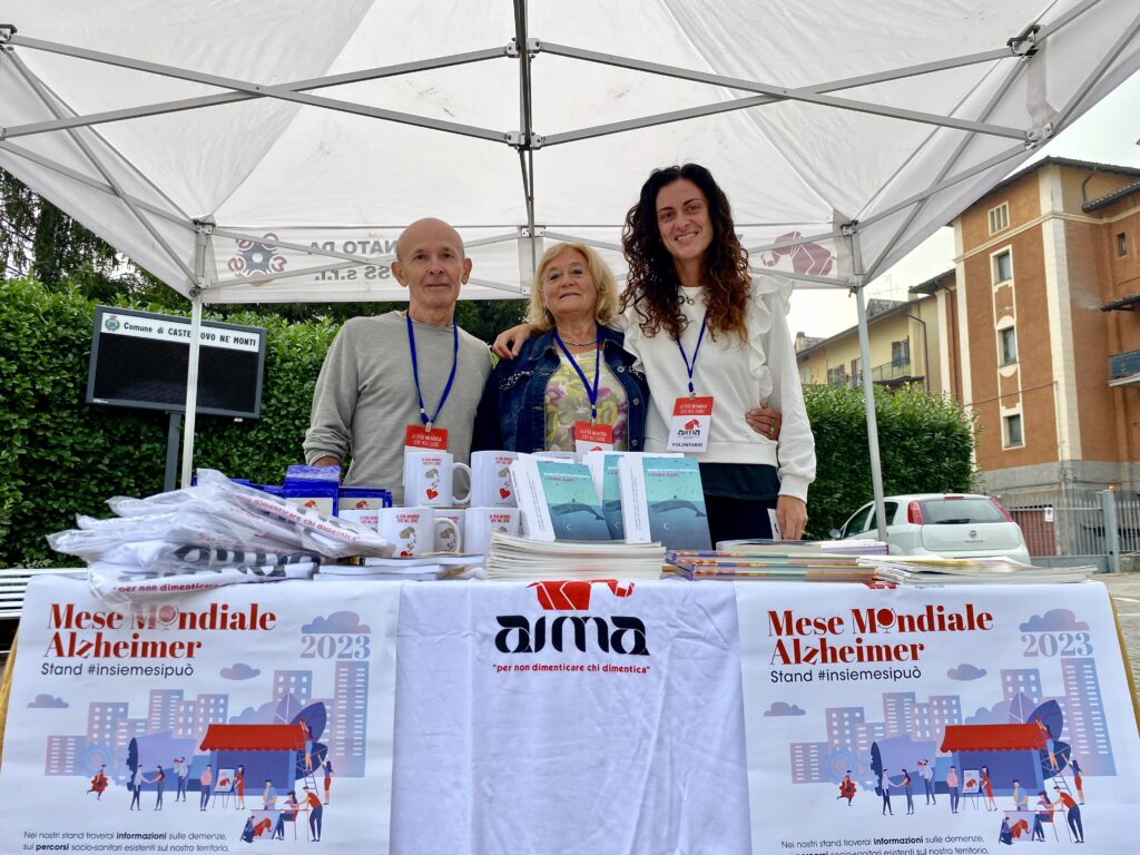 Fotografia dello stand con i volontari di AIMA Reggio Emilia per la campagna #insiemesipuò del Mese Mondiale Alzheimer 2023 in piazza Gramsci a Castelnovo ne' Monti