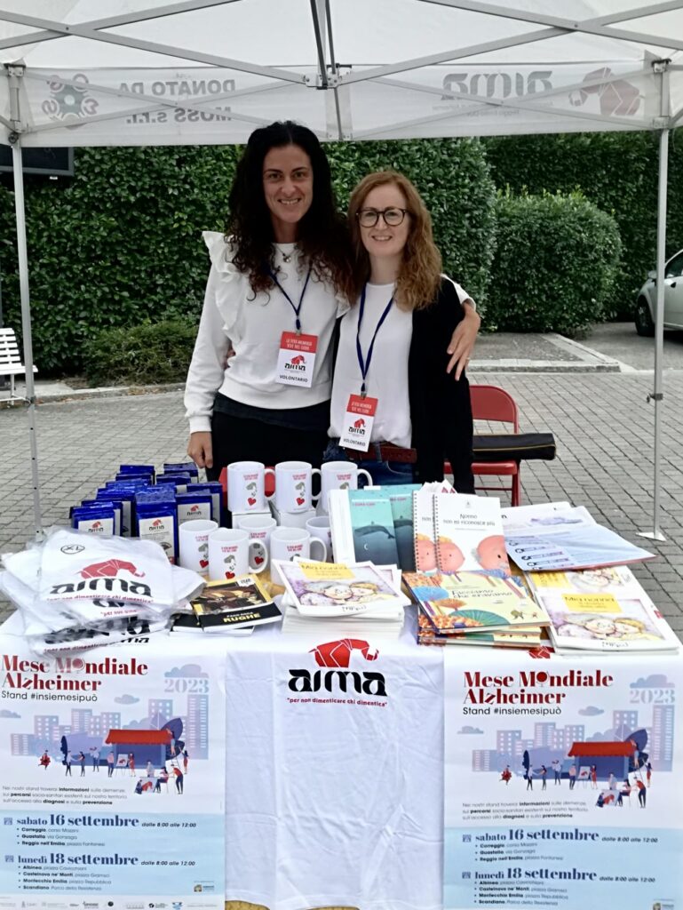 Fotografia dello stand con i volontari di AIMA Reggio Emilia per la campagna #insiemesipuò del Mese Mondiale Alzheimer 2023 in piazza Gramsci a Castelnovo ne' Monti