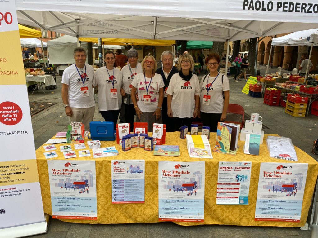Fotografia dello stand con i volontari di AIMA Reggio Emilia per la campagna #insiemesipuò del Mese Mondiale Alzheimer in piazza Fontanesi a Reggio Emilia