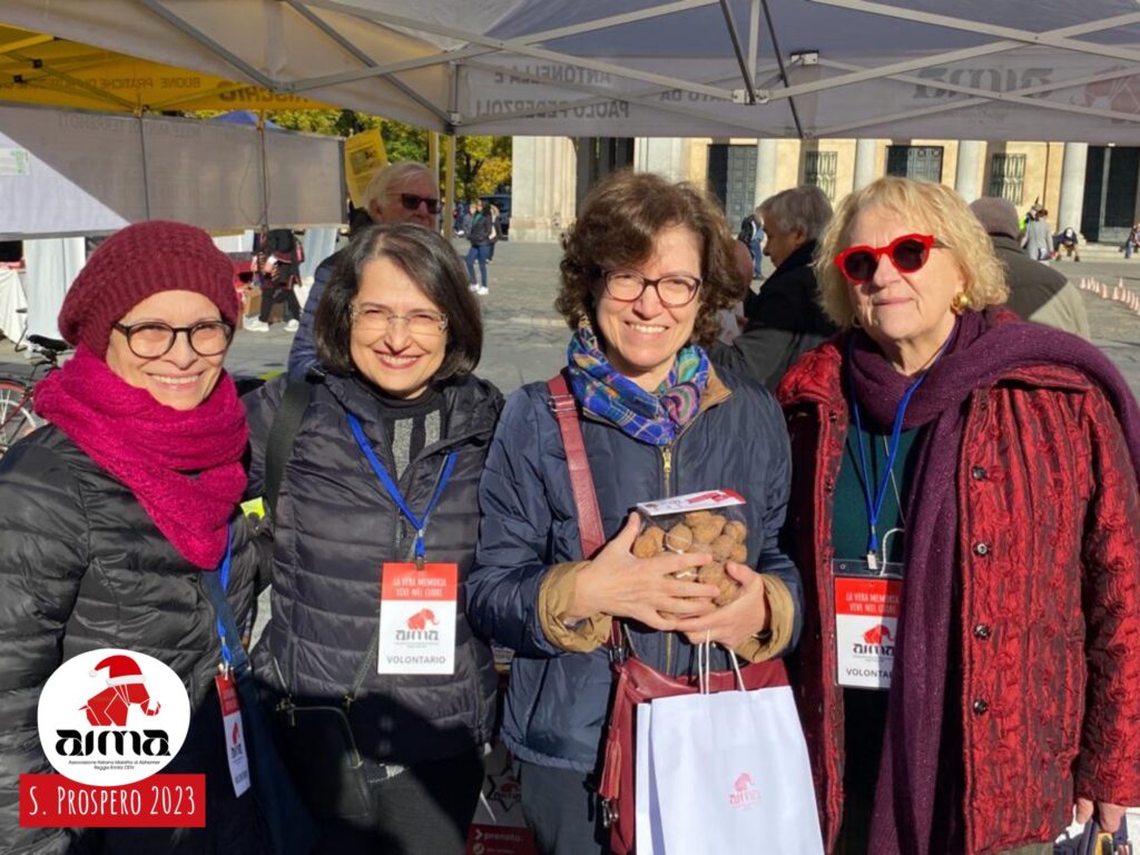 Foto di gruppo: volontarie AIMA davanti allo stand con le Noci della Memoria in piazza Martiri nel giorno della Festa di San Prospero, 24 novembre 2023
